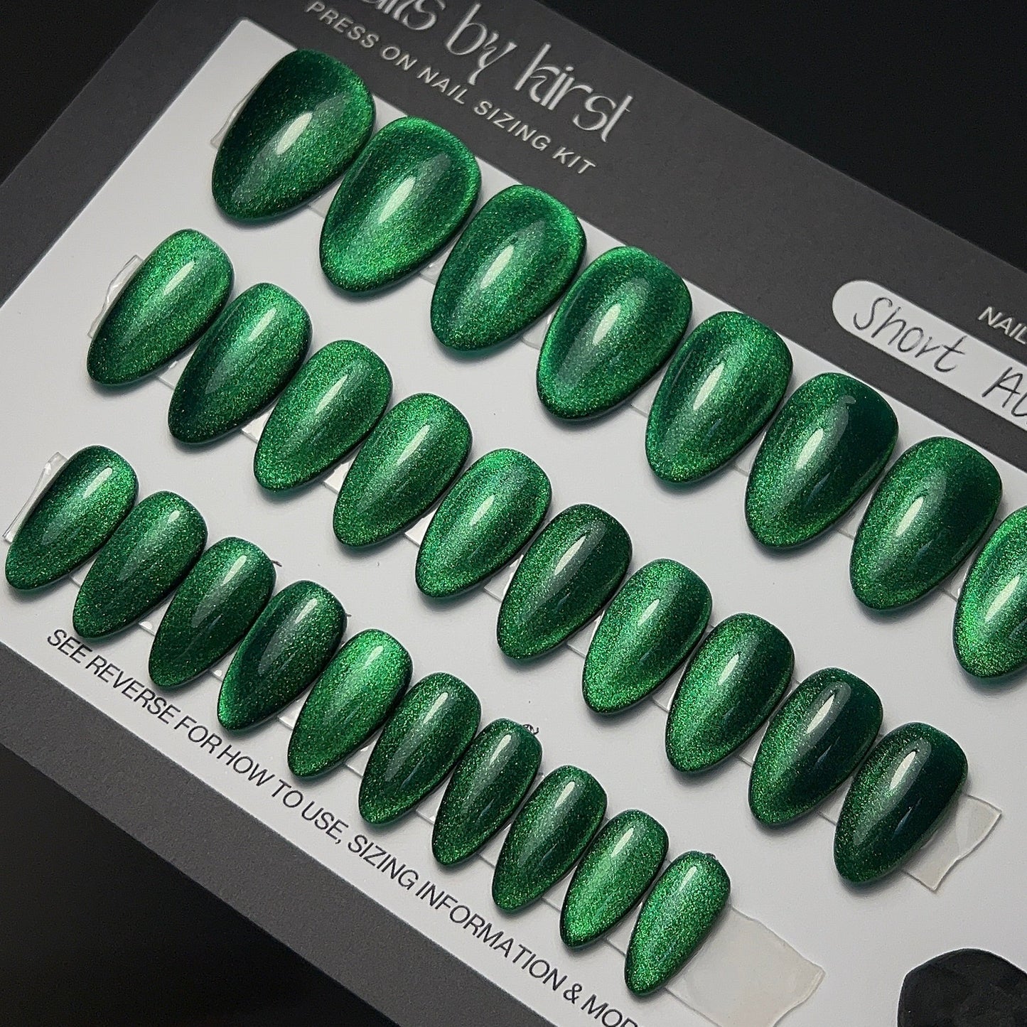 Set of green glittery press-on nails on a sizing kit
