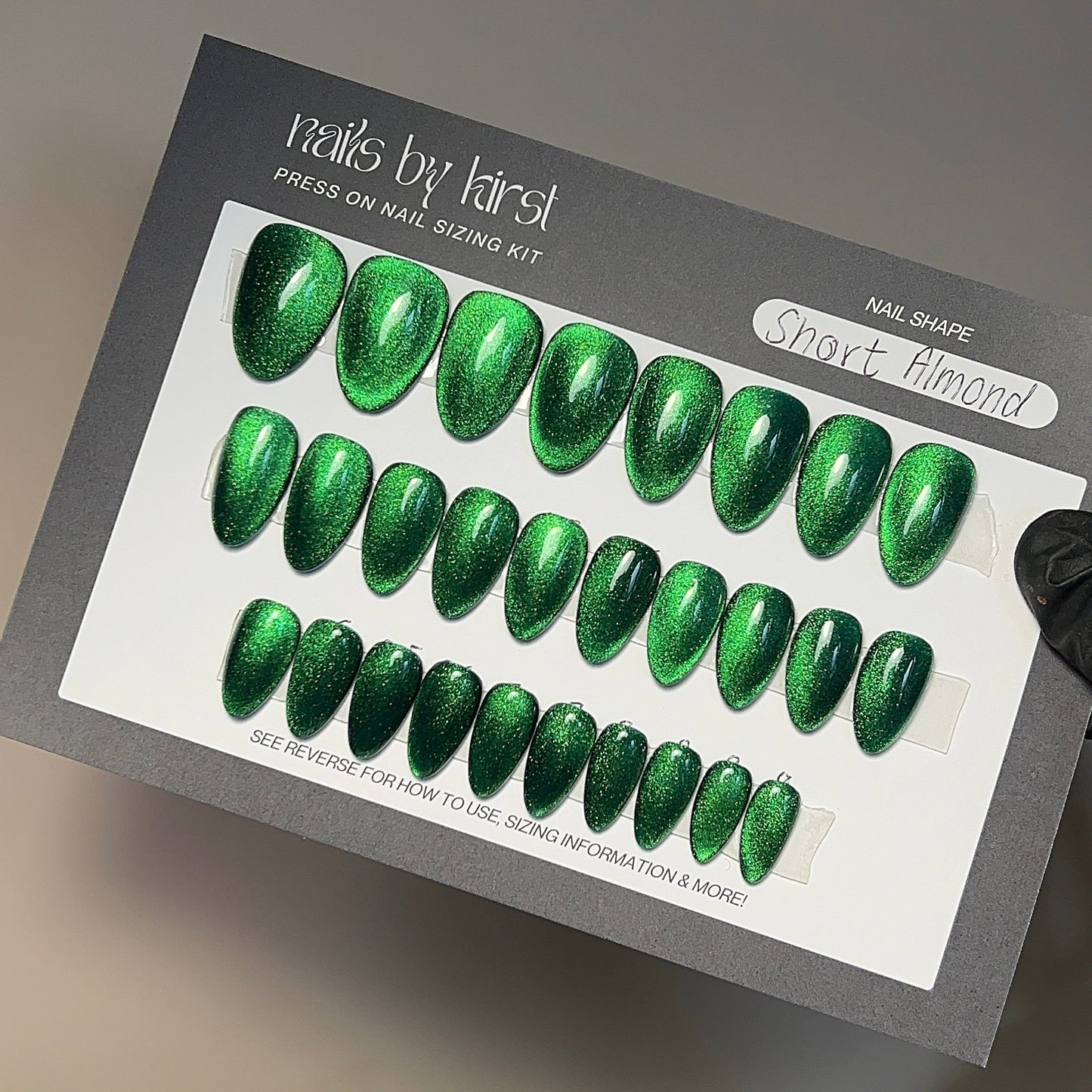 Green nail art design kit held by a hand on a neutral background