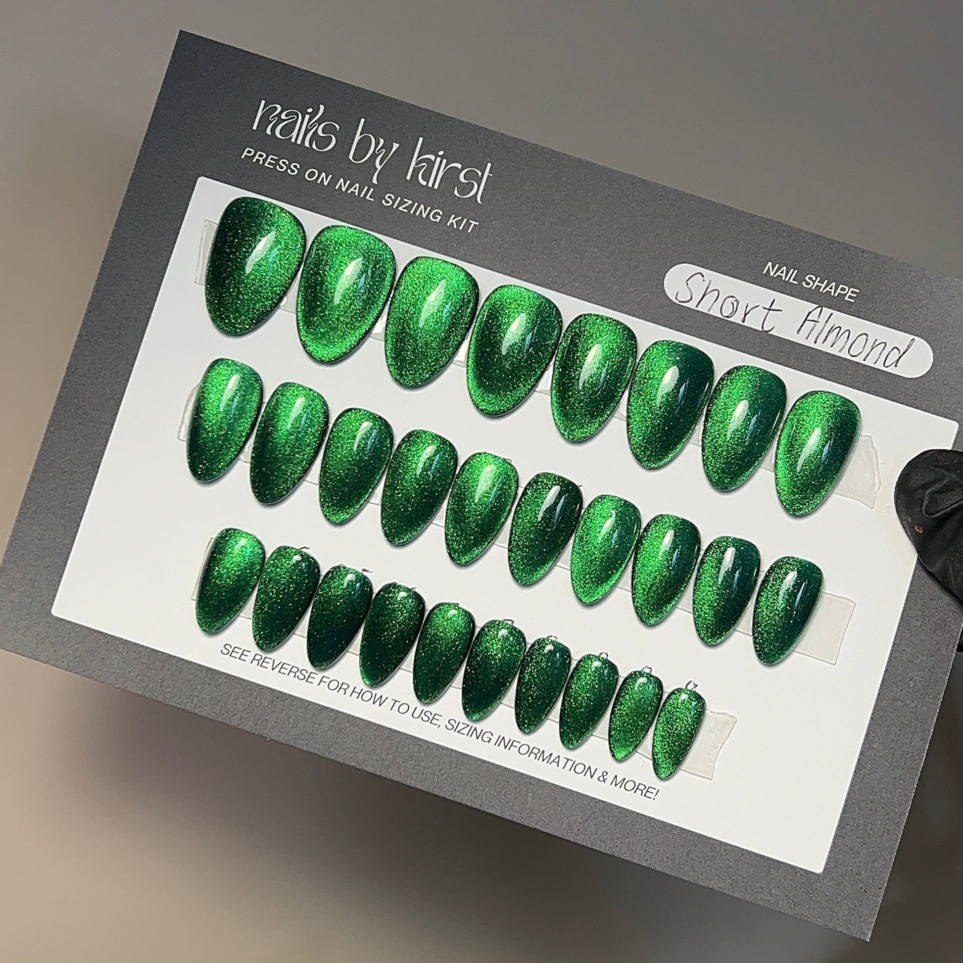 Green nail art design kit held by a hand on a neutral background