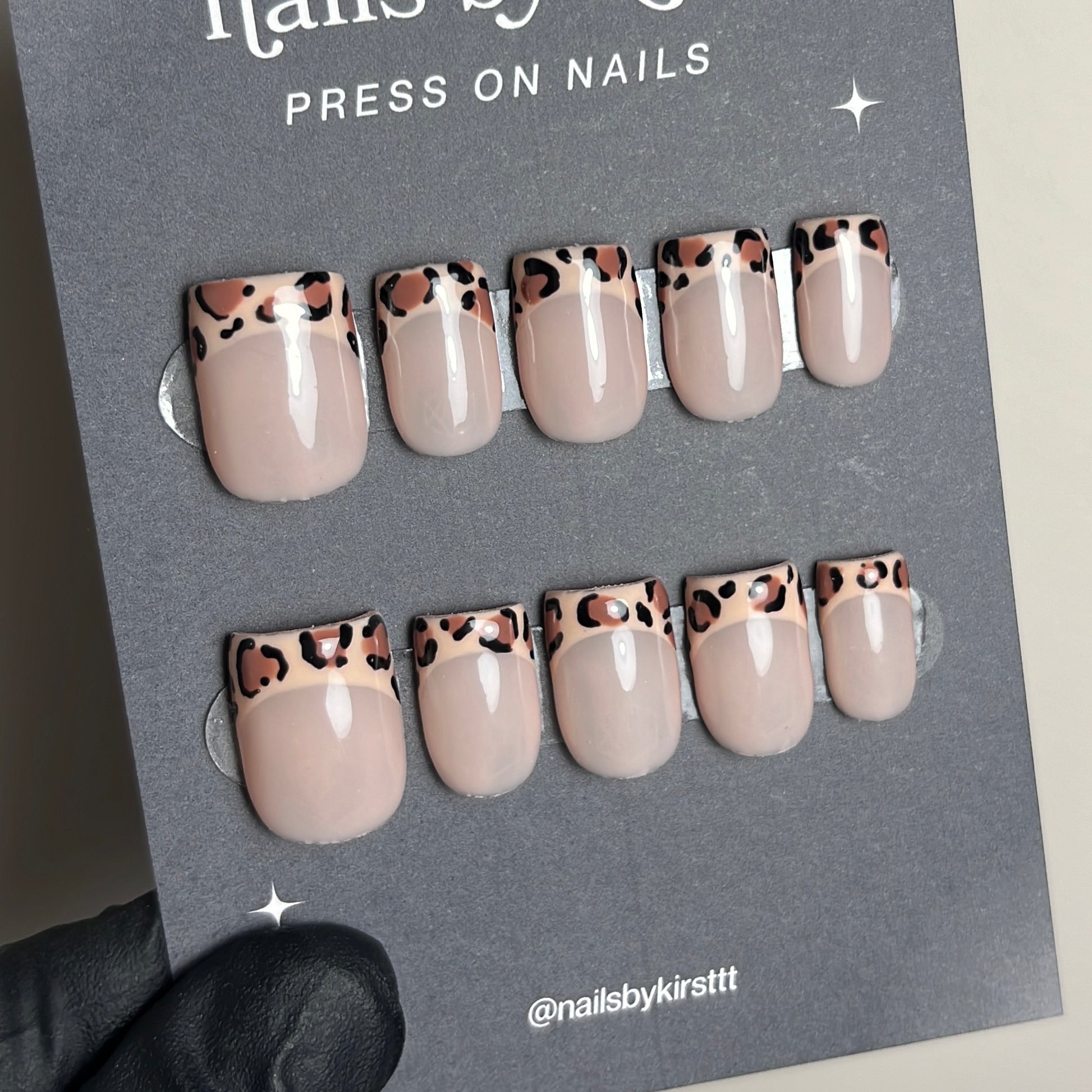 French tip press on nails on a backing card. The nails have leopard print on the french tip part. 