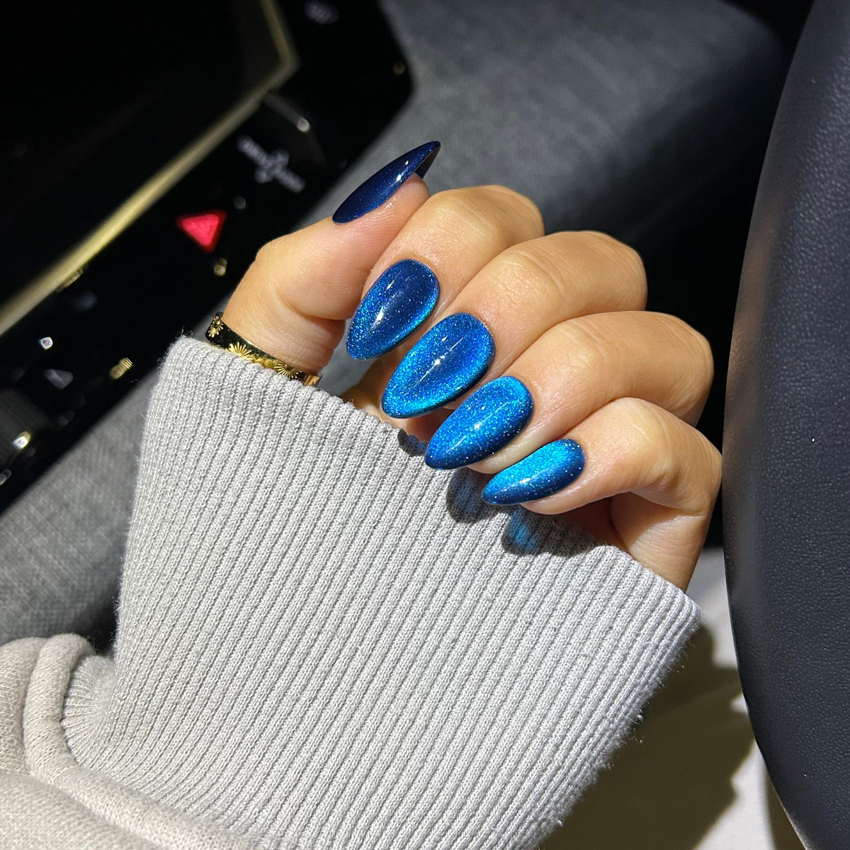 Hand with blue nail polish on a car dashboard