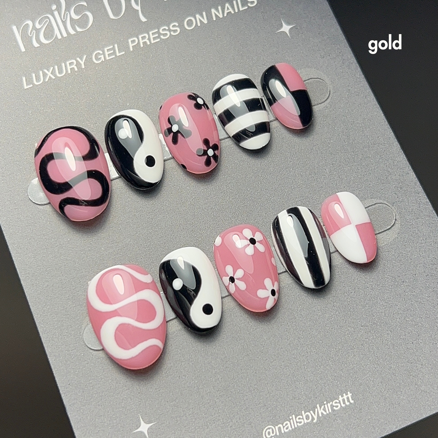 Set of mix and match nail designs with pink, black, and white patterns on a grey backing card.