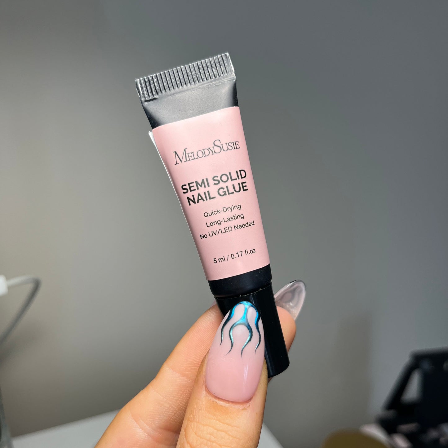 a hand holding a small tube of "Melody Susie semi solid nail glue"