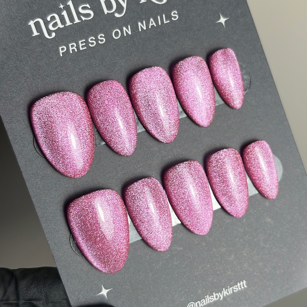 A set of pink glitter press-on nails displayed on a card