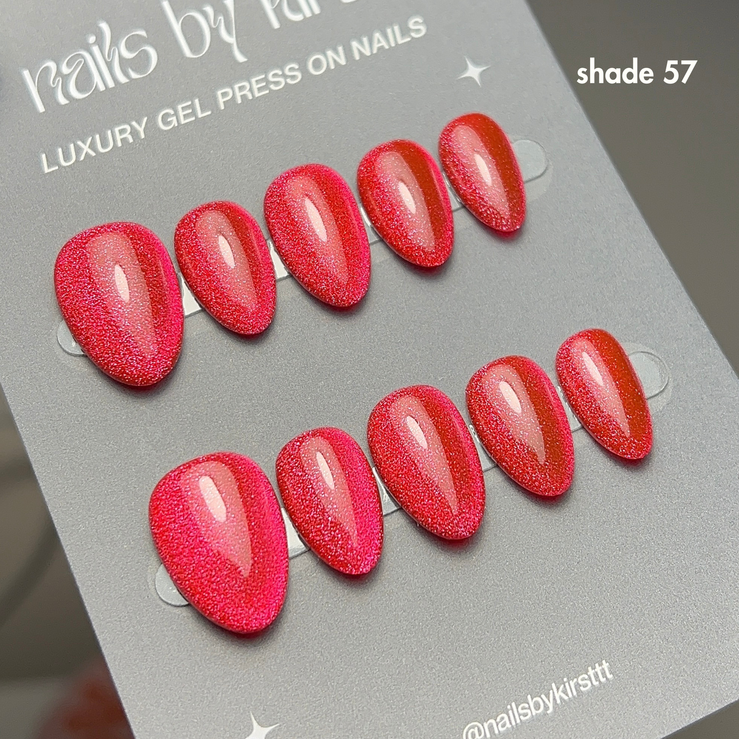 red cat eye gel press-on nails on a grey card with 'nails by kirsttt' branding.