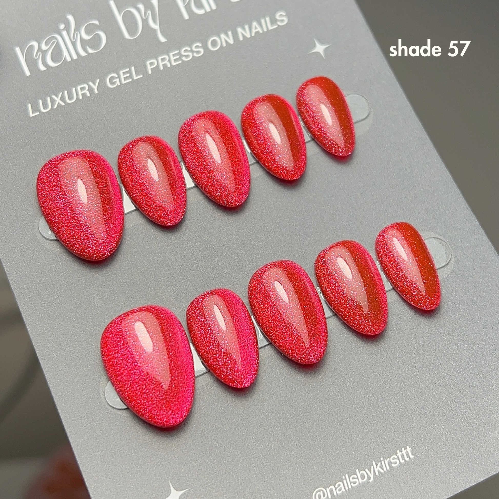 red cat eye gel press-on nails on a grey card with 'nails by kirsttt' branding.